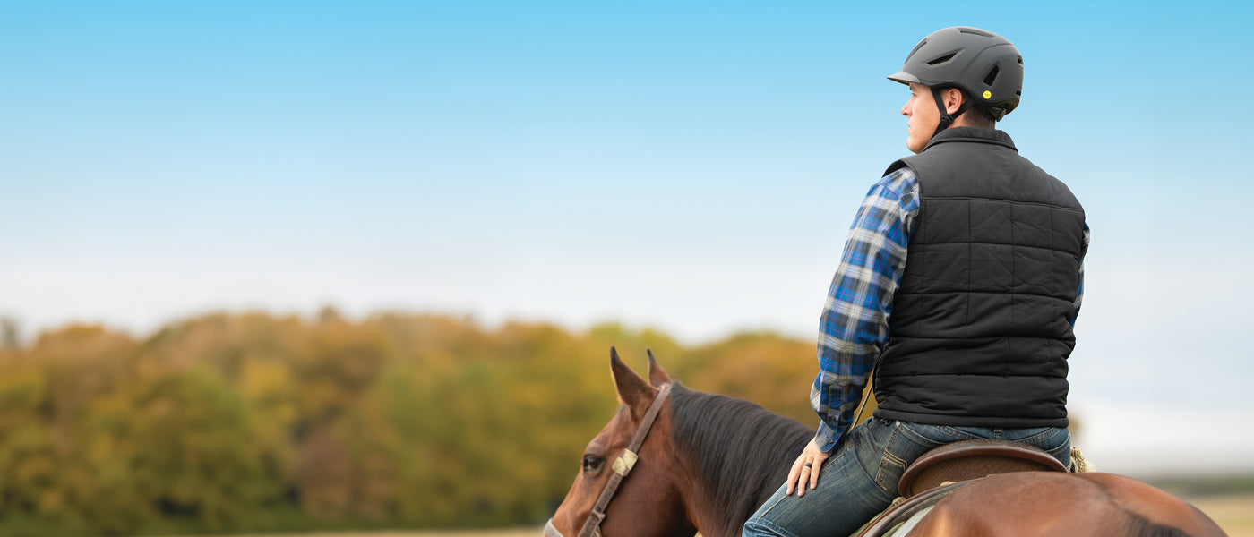 Rider wearing a black equestrian helmet while riding a horse outdoors